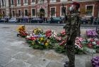 Kwiaty składają pozostałe delegacje będąc po lewej stronie zdjęcia. Po prawej stronie kadru kwiaty leżą przed pomnikiem i żołnierze pełniący wartę honorową..