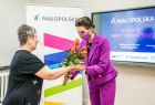  Alt: W klasie szkolnej dyrektor szkoły przekazuje kwiaty Marcie Malec-Lech z zarządu województwa.