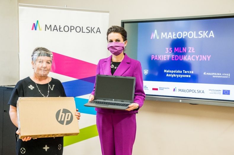 Dwie eleganckie kobiety: Marta Malec-Lech z zarządu województwa oraz dyrektor szkoły stoją i trzymają nowe laptopy.