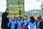 Wicemarszałek Łukasz Smółka trzyma w ręce mikrofon i rozmawia z dziećmi na boisku. Z tyłu napis Spełniły się nasze marzenia.