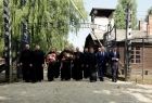 Grupa osób przechodzi przez bramą obozu koncentracyjnego Auschwitz