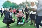 Wicemarszałek Łukasz Smółka rozmawia z dziewczynką siedzącą na wózku inwalidzkim.