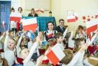 Marta Malec-Lech z zarządu województwa wraz z dziećmi machającymi flagą.