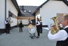 Orkiestra Dęta OSP we Włosani gra na dziedzińcu nowoczesnego budynku.
