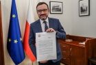 Wicemarszałek Tomasz Urynowicz trzyma pismo. W tle flagi Polski i Unii Europejskiej.