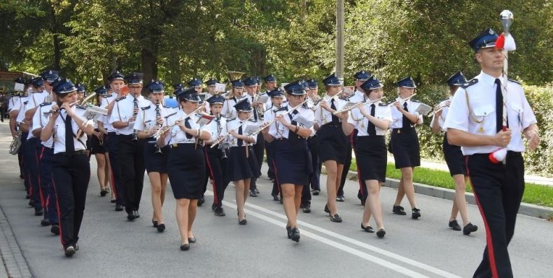Orkiestra Dęta OSP Ochotnica Dolna gra podczas przemarszu ulicą. W tle zieleń