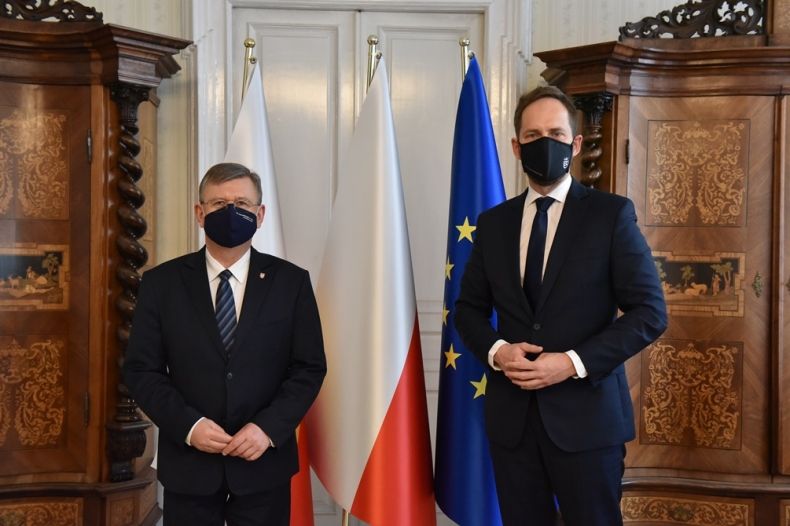 marszałek Witold Kozłowski i Jakub Kwaśny - przewodniczący rady miejskiej w Tarnowie stoją na tle flag w gabinecie