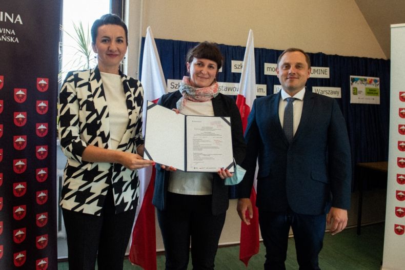 Marta Malec Lech z zarządu województwa stoi wraz z pozostałymi uczestnikami i trzyma podpisaną umowę.