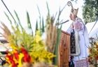 Metropolita Krakowski abp. Marek Jędraszewski stoi przy ołtarzu polowym ustawionym na scenie, przy ołtarzu widać bukiet wykonany ze zboża i kwiatów. 