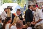Marszałek Witold Kozłowski częstuje pokrojonym chlebem dożynkowym zaproszonych gości 
