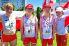 Czwórka sportowców w czerwonych czapeczkach trzyma flagę Polski