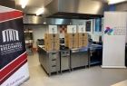 Nowe urządzenia stoją na blacie w kuchni. Obok stoją banery z napisem Małopolska Szkoła Gościnności i Instytut Rozwoju Obszarów Wiejskich.