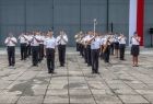 Wojskowa orkiestra lotników gra przed hangarem.