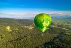 Zielony balon lata nad lasem, na tle nieba i zieleni