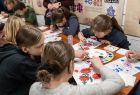 Grupa dzieci maluje tradycyjne wzory na kartkach papieru