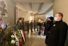 Uczestnicy uroczystości składają wiązankę kwiatów pod tablicą pamiątkową w kościele w Oświęcimiu