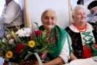 Starsze kobiety w strojach regionalnych trzymają bukiety kwiatów