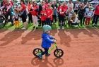 dziecko jedzie na rowerze, z bosku uczestnicy dopingują je