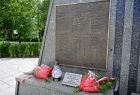 Widok na grybowski Pomnik poległych w II wojnie światowej. Z bliska tablica upamiętniająca poległych z imionami i nazwiskami
