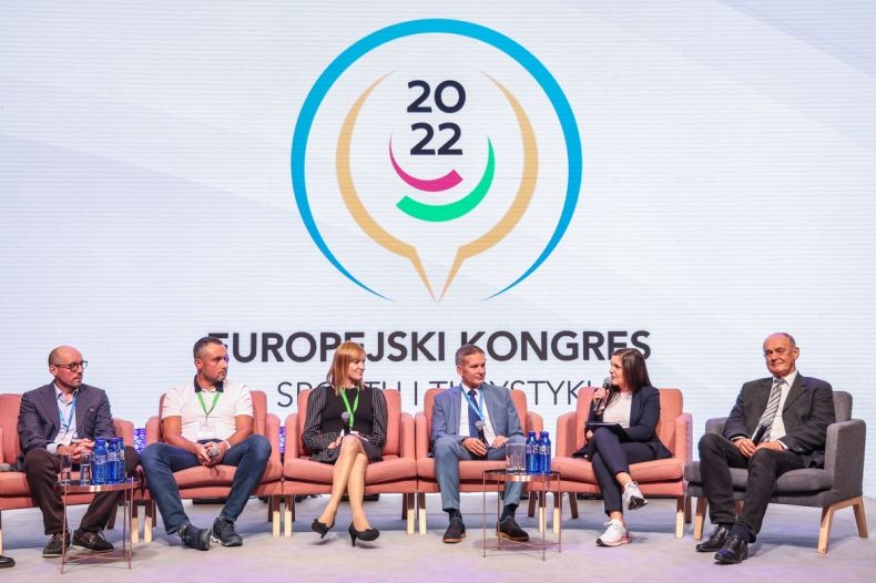 Wszystkie osoby siedzą na fotelach, są widoczne z przodu. W tle widoczne logo I Europejskiego Kongresu Sportu i Turystyki. 