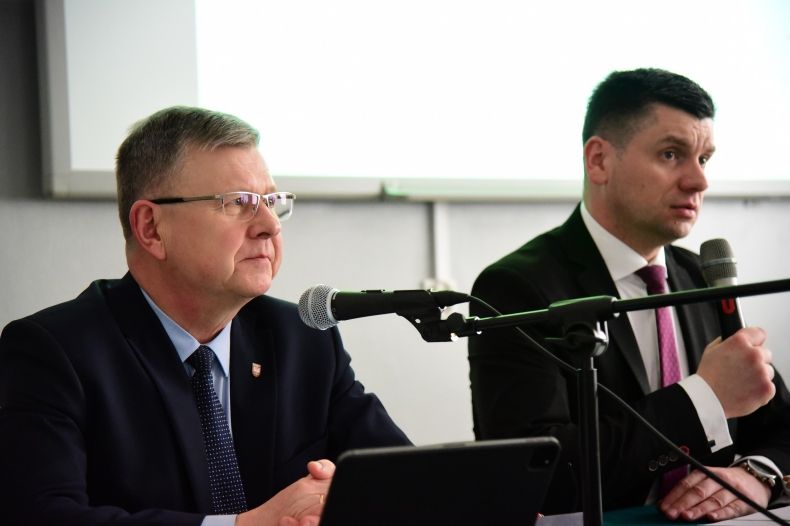 Marszałek Witold Kozłowski i wicemarszałek Łukasz Smółka siedzą przy stole z mikrofonami.