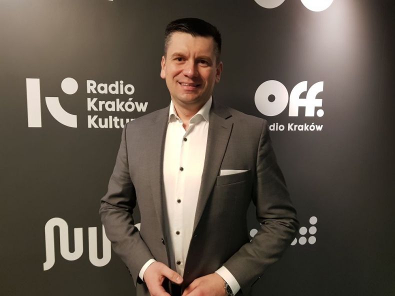 Wicemarszałek Łukasz Smółka stoi na tle ścianki z napisem Radio Kraków Kultura.