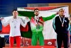Trzech zawodników z medalami na szyi prezentujący flagi krajów. Pierwszy z lewej zawodnik z Polski. 