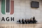 Orkiestra gra na sali sportowej. Na ścianie widoczne logo AGH.