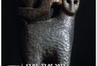 Plakat z informacją o wystawie na tle fotografii przedstawiającej rzeźbę kota w drewnie. 