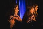 Trzy dziewczyny z zespołu grają na fletach poprzecznych.