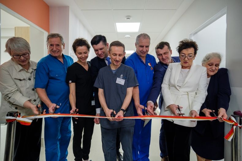 Wicemarszałek Łukasz Smółka przecina wstęgę na szpitalnym korytarzu.
