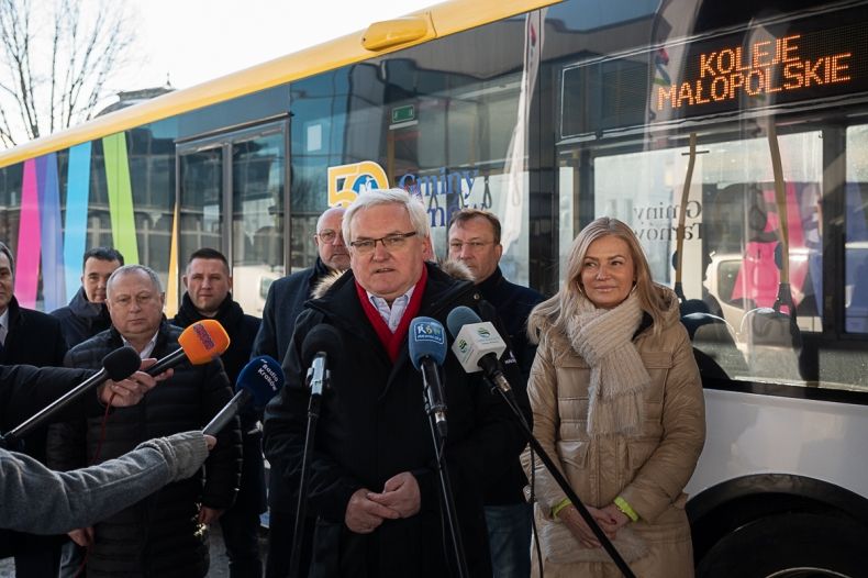 Wicemarszałek Józef Gawron przemawia do mikrofonów. W tle autobus z napisem Koleje Małopolskie.