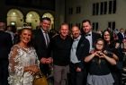 Pamiątkowa fotografia. Marszałek Łukasz Smółka i dyrektor Opery Krakowskiej Piotr Sułkowski oraz dziewczynka wraz z opiekunami, pokazująca palcami znak serca