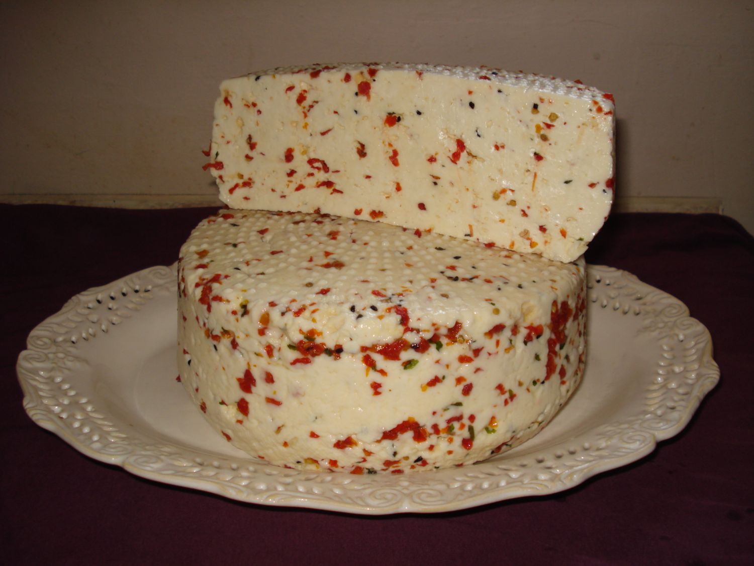 Na białym talerxzu dwa kawałki białego sera z kolorowymi ziołami.