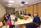 zdjęcie przedstawia osoby siedzące przy prostokątnym stole,