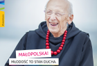 Tło nieba, Na pierwszym planie zakonnik w habicie, ojciec Leon Knabit w czrwonych koralach. Na zdjęciu napis: Małopolska. Młodość to stan ducha