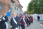kilkunastoosobowa grupa mężczyzn ze sztandarami idzie uliczką Starego Miasta w Krakowie
