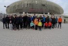 grupa kilkudziesięciu osób stoi na chodniku na tle hali widowiskowo-sportowej