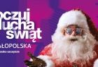 Plakat z napisem po lewej: Poczuj ducha świa. małopolska. tu mieszka szczęście. Po prawej św. Mikołaj z dłońmi wyciągniętymi do przodu