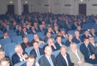 w kilku rzędach foteli siedzą ludzie, ubrani w galowe stroje