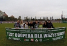 zielony transparent z napisem Test Coopera dla wszystkich, ponad nim grupka młodych ludzi