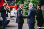 Przewodnicząca Nowogórska w towarzystwie odwróconej tyłem osoby przekazuje kluczyki strażakowi. W tle stoi samochód strażacki.