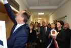 Marszałek Jacek Krupa odsłania tablicę nad drzwiami do sali. Obok grupa osób z przewodniczącą sejmiku Urszulą Nowogórską, która trzyma szarfę.