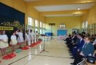 Grupa osób siedzących po prawj stronie obserwuje występ artystyczny dzieci po lewej stronie.