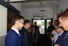 Grupa osób ustawionych w dwóch rzędach. W środku ksiądz z kropidłem wzniesionym do góry.