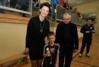 Trzy osoby stoją na parkiecie hali sportowej. Pierwsza z lewej przewodnicząca sejmiku U. Nowogórska. Obok niej chłopiec w stroju sportowym trzymający puchar.