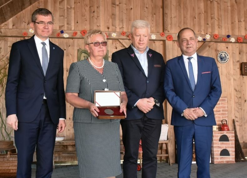 Cztery osoby na scenie. Druga z lewej kobieta trzyma medal w pudełku. Trzeci z lewej radny Stanisław Pasoń.