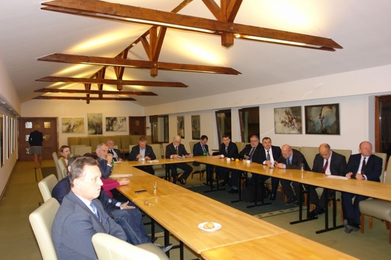 Grupa osób siedzących przy dwóch równoległych stołach.Na pierwszym planie marszałek Jacek Krupa.