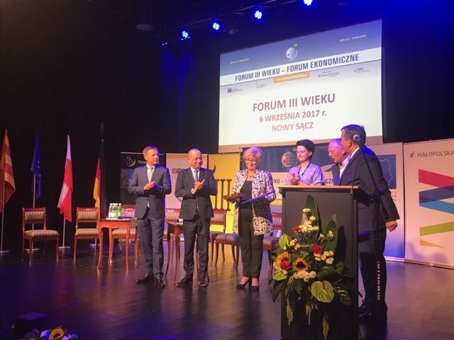 Grupa osób stoi na scenie.