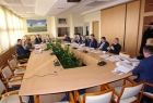 Grupa osób siedzących przy prostokątnym stole.